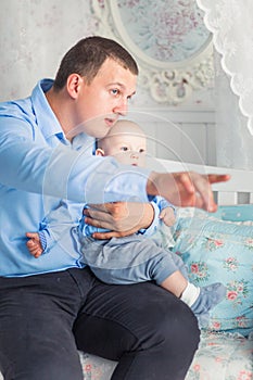 Father and son are sitting in the children`s room. Dad shows something to his son
