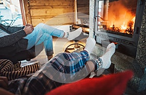 Father with son sitting in comfortable armchairs in their cozy country house near fireplace and enjoying a warm atmosphere and