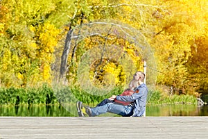 Father and son are sitting on the dock. Autumn, sunny. Side view