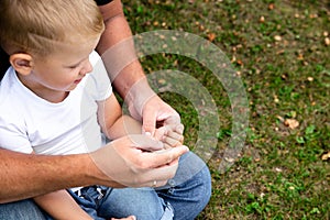Father and son are sitting on the grass in park outdoor closeup. Father teaches son, tells a story, plaing. Kindred love.