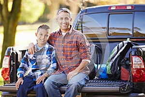 Father And Son Sitting In Pick Up Truck On Camping Holiday