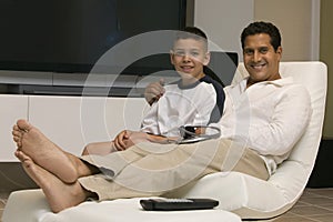 Father and Son sitting Together on chair in Living Room portrait