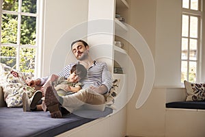Father And Son Sleeping On Window Seat At Home Together