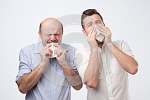 Father and son are sneezing being ill
