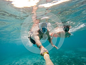 Father and son snorkel in shallow water on coral fish