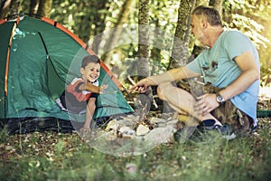 Father and son spending happy leisure time together outdoors in forest trees background