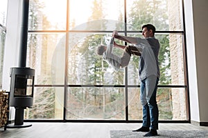 Father and son spending time together, man throwing up his son at home in living room, copy space. Father`s day concept