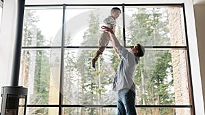 Father and son spending time together, man throwing up his son at home in living room, copy space. Father`s day concept