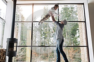 Father and son spending time together, man throwing up his son at home in living room, copy space. Father`s day concept