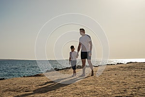 Father and  son  spending time together sea vacation. Young man, little boy walking beach Fathers day. Family with one child.