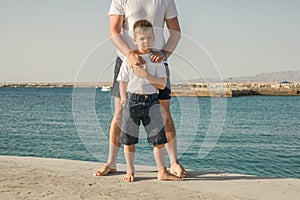 Father and  son  spending time together sea vacation. Young man, little boy walking beach Fathers day. Family with one child.