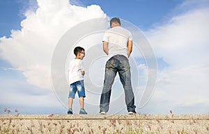 Father and son standing on a stone platform and pee together