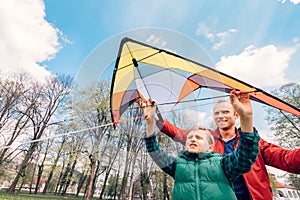 Father and son start to fly a kite in sky