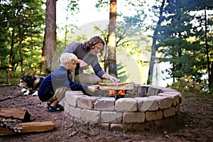 Father and Son Starting Campfire in Fire Ring at Campground Overlooking a Lake in the Woods