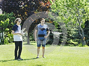 Father and son on summer day flying drone on countryside.