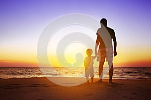 Father and son at sunset beach photo