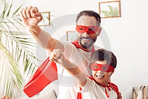 Father and son in superheroe costumes at home standing hands forward confident superpowers