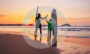 Father and son surfers stay on the sunset beach