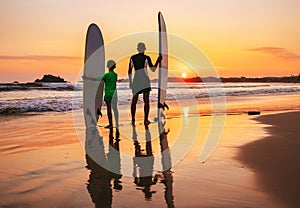 Father and son surfers stay on the sunset beach