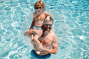 Father and son swimming in pool, summer family. Child with dad playing in swimming pool. Family in pool. Summer vacation