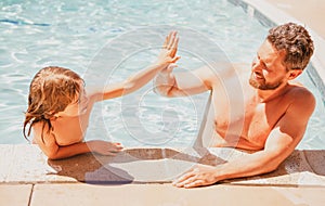 Father and son swimming in pool, summer family. Child with dad playing in swimming pool. Family time. Summer vacation