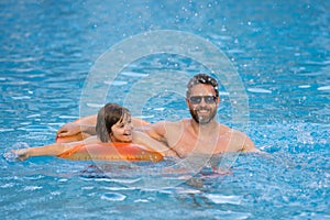 Father and son swimming in pool, summer family weekeng. Little kid boy with father splashing in swimming pool. Family