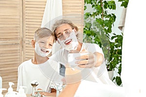 Father and son taking selfie with shaving foam on faces