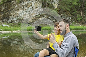 Father with son taking selfie. smiling man and young boy playing outdoors