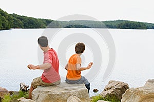 Father and son throwing rocks into lake