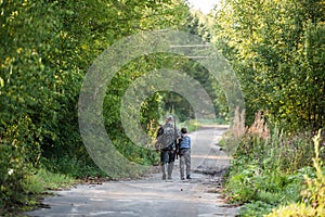 Father and son together hunting together. Walking the road in a forest.