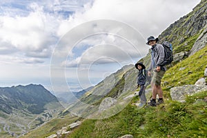 Father and son on top of the mountain, hiking with bakpacks in sunny day. Mountain scenery