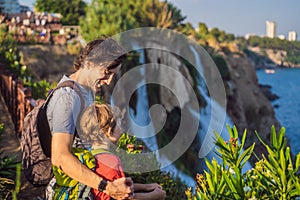 Father and son tourists on the background of Duden waterfall in Antalya. Famous places of Turkey. Lower Duden Falls drop