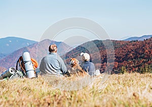 Father and son travelers with their beagle dog sit together in m