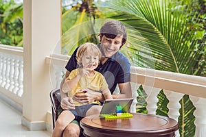 Father and son in tropics talking with friends and family on video call using a tablet and wireless headphones