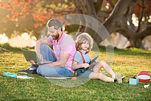 Father and son use laptop, dad and school boy child looking tablet. Outdoor distance learning. Outdoor education.