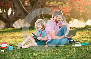 Father and son use laptop, dad and school boy child looking tablet. Outdoor distance learning. Outdoor education.