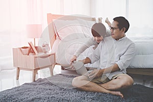 Father and son is using Computer Laptop for Education together at home is the Bedroom