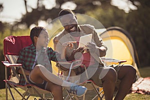 Father and son using digital tablet in park