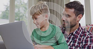 Father and son using laptop in a comfortable home 4k