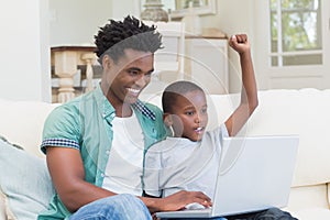 Father and son using laptop on the couch