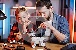 Father with son using screwdrivers for fixing robot dog