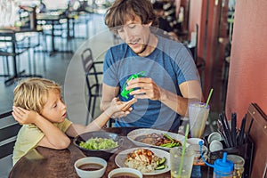 Father and son using wash hand sanitizer gel before eating in a cafe