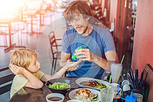 Father and son using wash hand sanitizer gel before eating in a cafe with sunlight