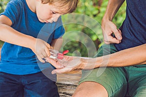 Father and son using wash hand sanitizer gel in the park before