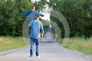 Father and son walk along the road holding hands