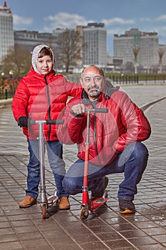 Father and son on a walk with scooters in winter