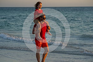 Father and son walk in sea beach. Concept of friendly family. Son on fathers shoulders piggyback ride. Dad with kid