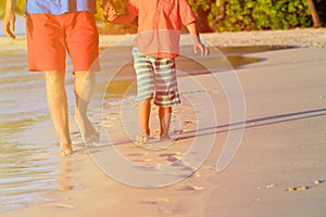 Father and son walking on beach leaving footprint