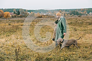 Father and son walking in a field with a dog