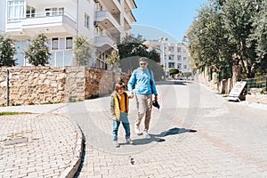 Father and son walking hand in hand in southern summer city. Dad man holding his kid's boy hand when taking a